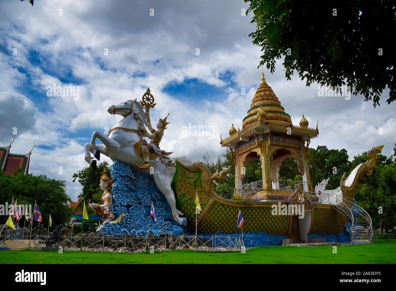 Kanchanaburi, Thailand 08.17.2019: Statue of Deity, god or goddess riding a detailed, ornately decorated white horse tracking a golden boat at the Wat Stock Photo