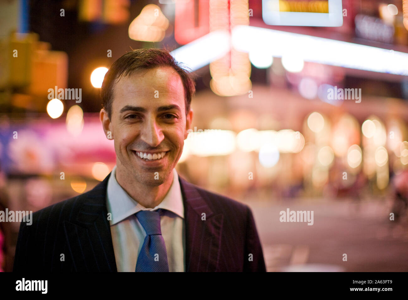 Portrait of a smiling mid-adult businessman at night with city lights ...