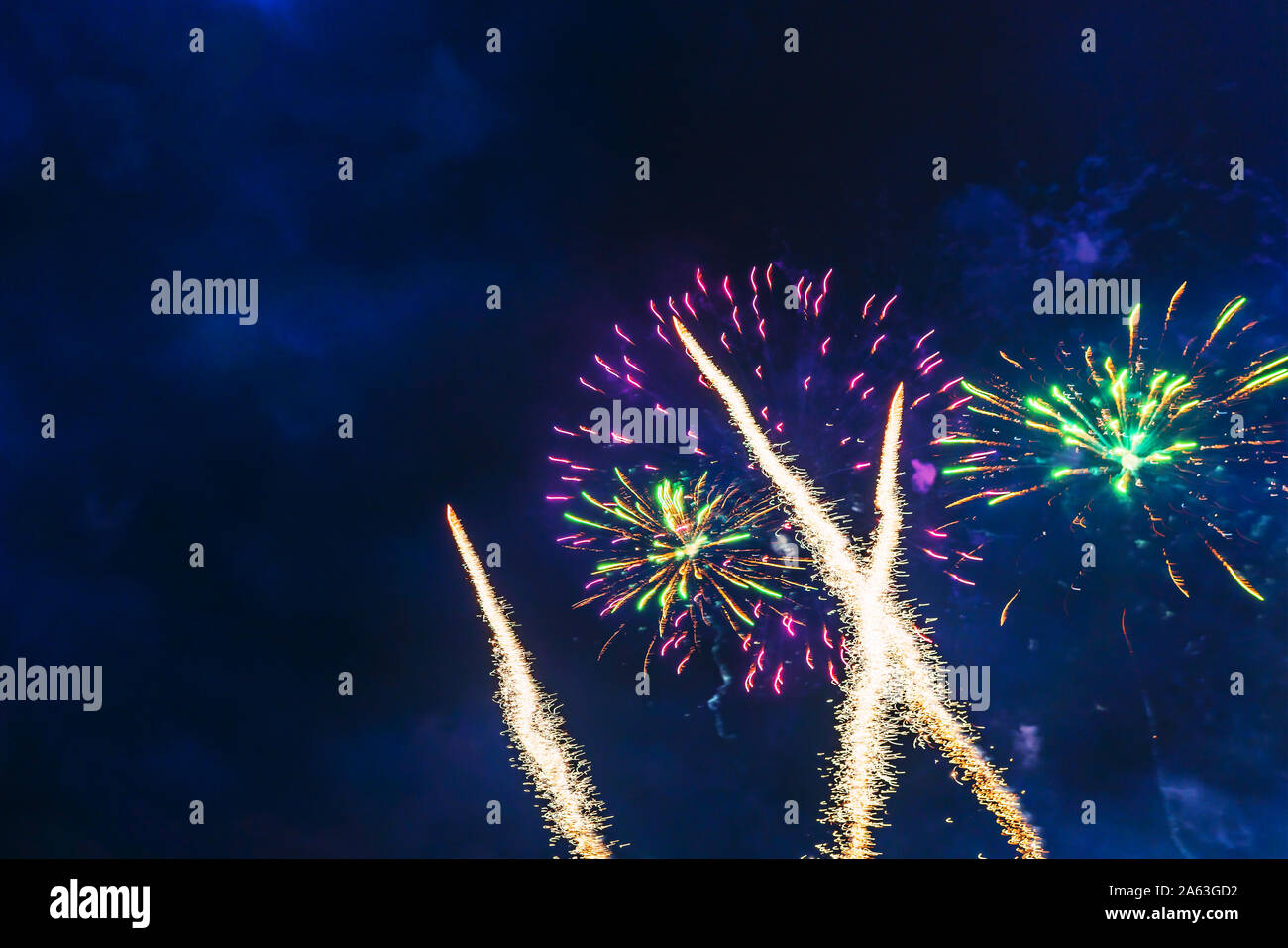 Inexpensive fireworks over the city sky, red, green and white with colour sparks. Bright and shiny. For any purpose. Celebration concept. Stock Photo