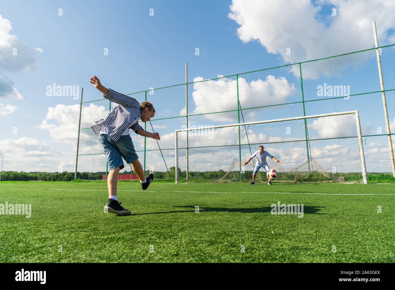 Happy father and excited son playing together soccer on a green