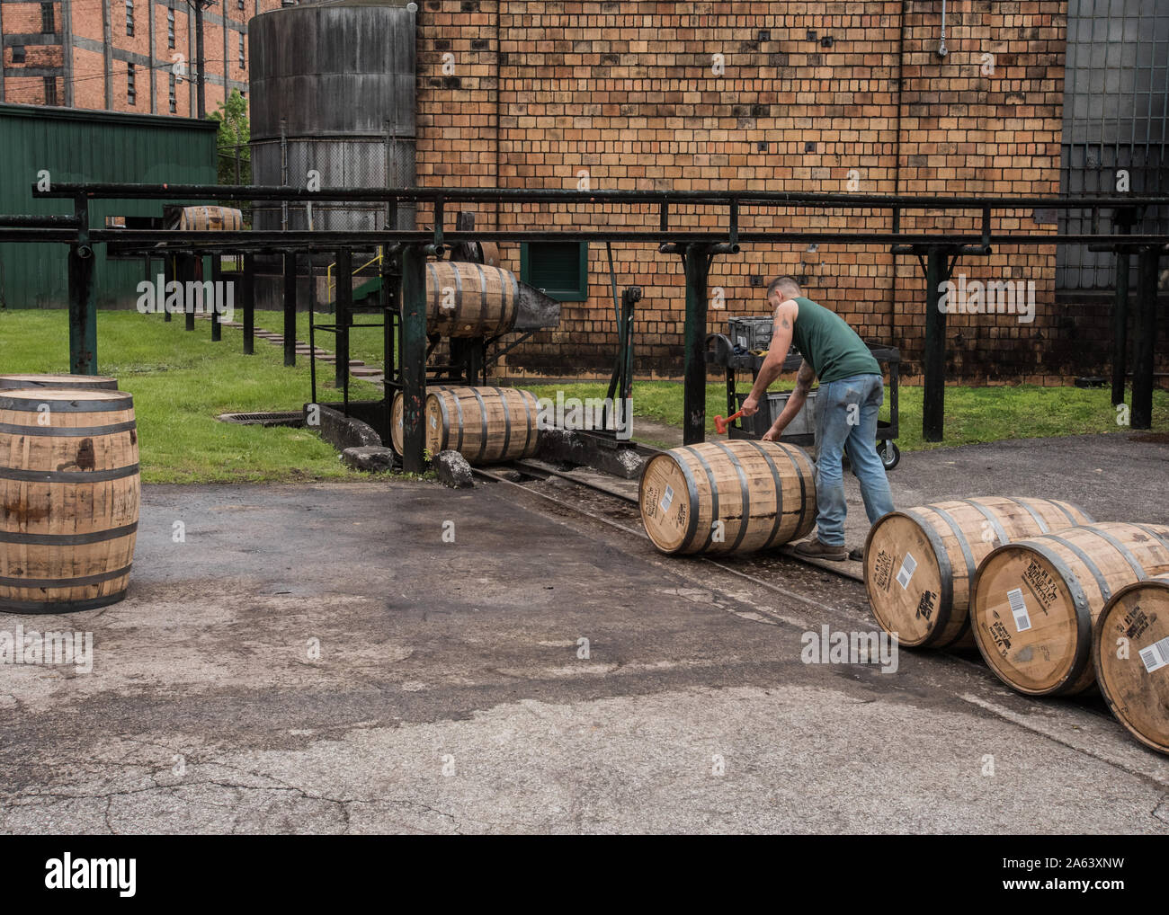 Versailles, United States: May 5th, 2016: Worker Sealing Barrels as they Roll outside bourbon distillery Stock Photo