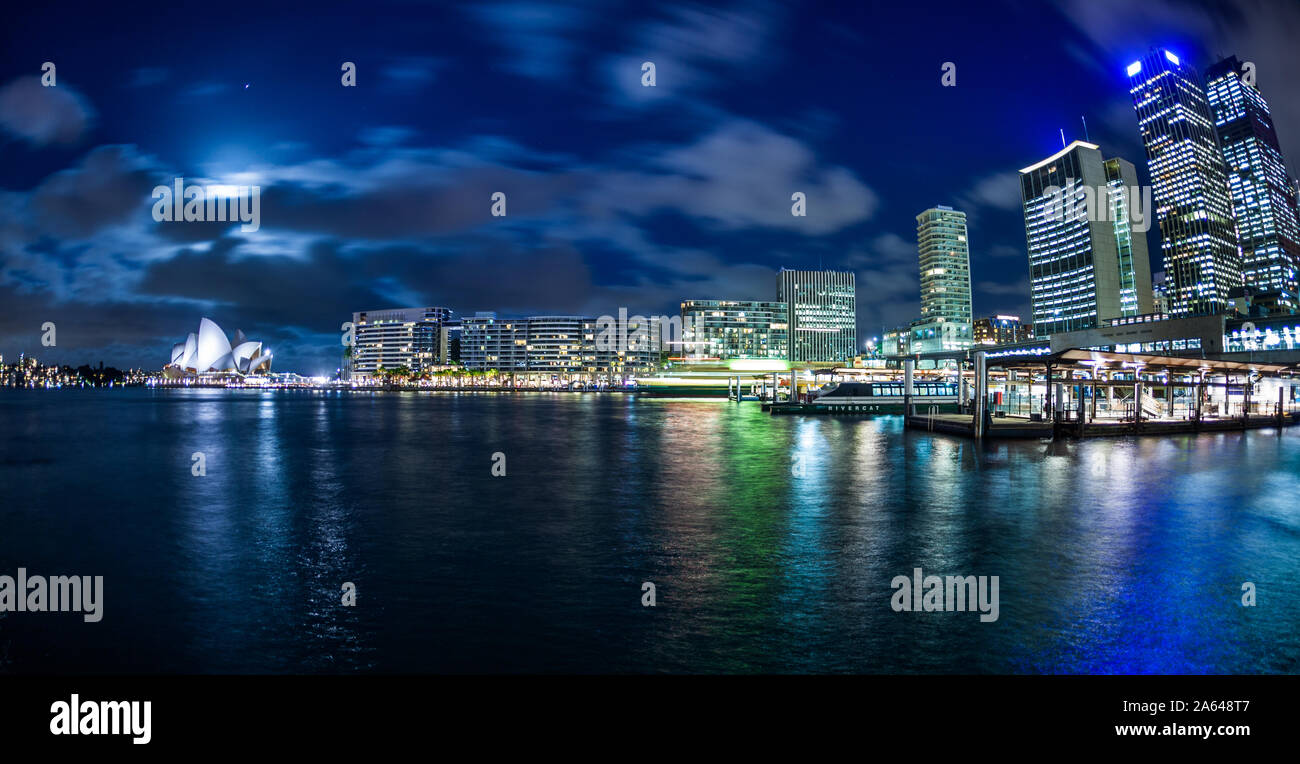 Sydney's Central Business District skyline, Circular Quay piers, and the Iconic Sydney Opera House at night. Sydney, NSW, Australia Stock Photo