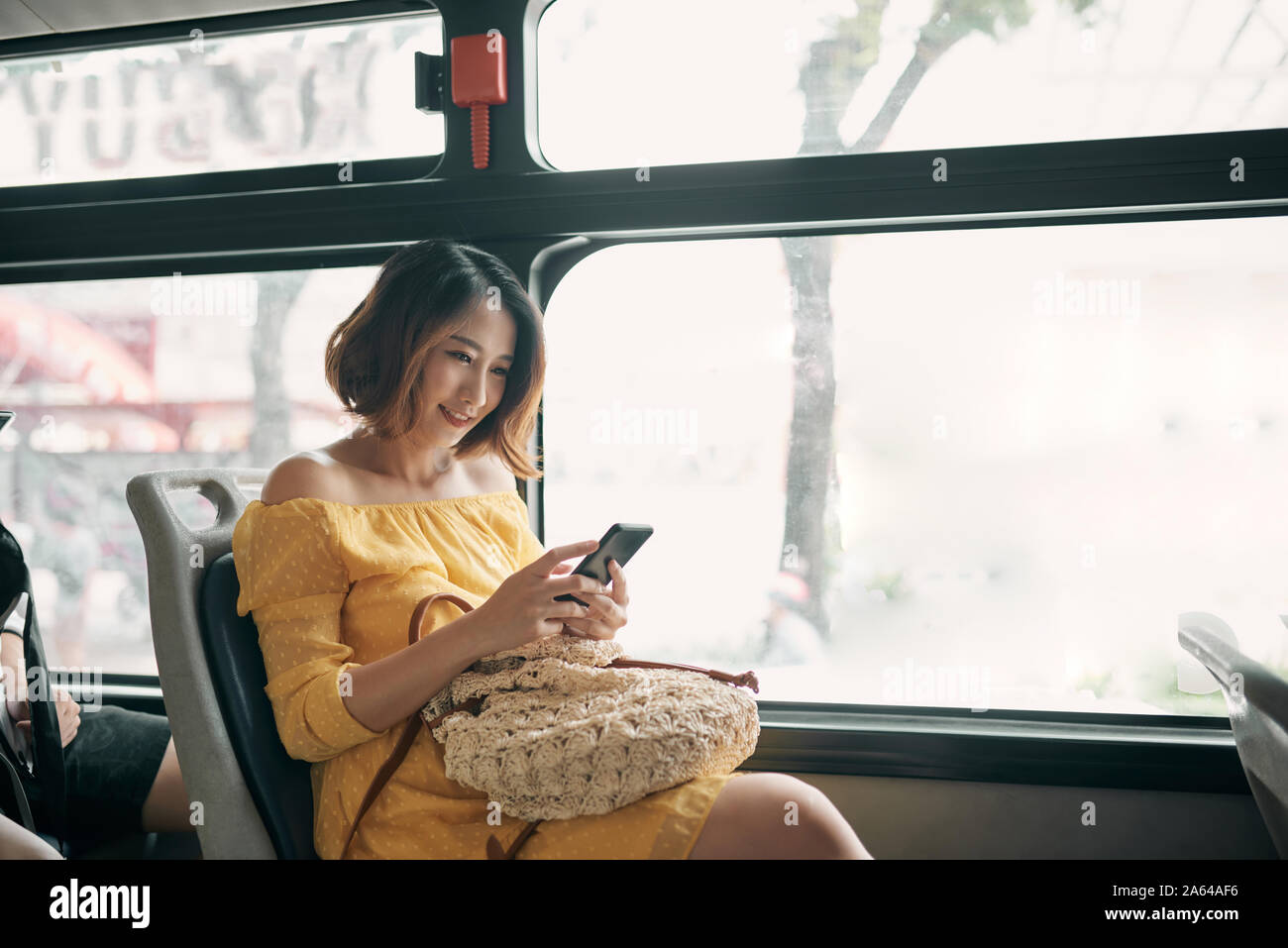 young beautiful asian woman browsing and typing messages in a public bus Stock Photo