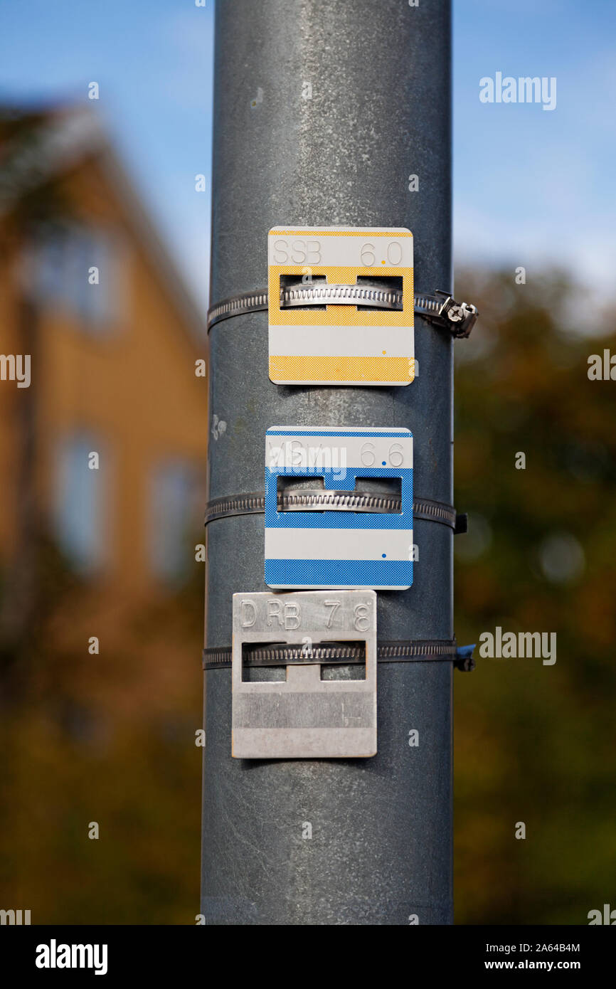 three metal signs with numbers and letters mounted on a lamp post, what