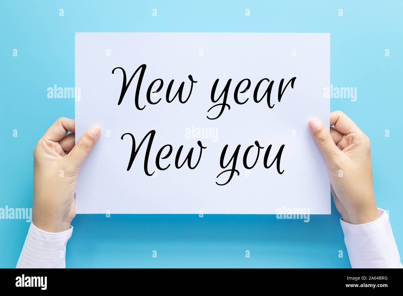 hand holding white paper with text New Year New You isolated on blue background. business goal , objective , motivation and inspiration concepts Stock Photo