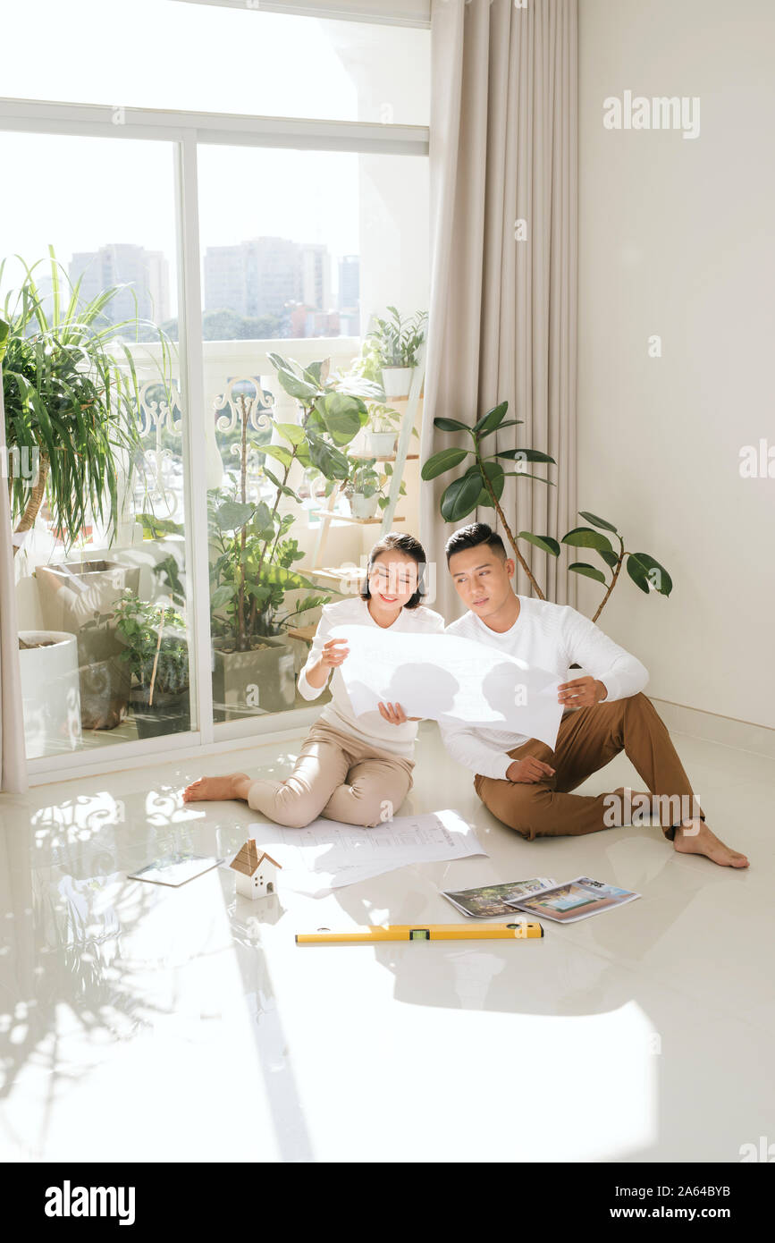 Attractive young asian adult couple looking at house plans. Stock Photo