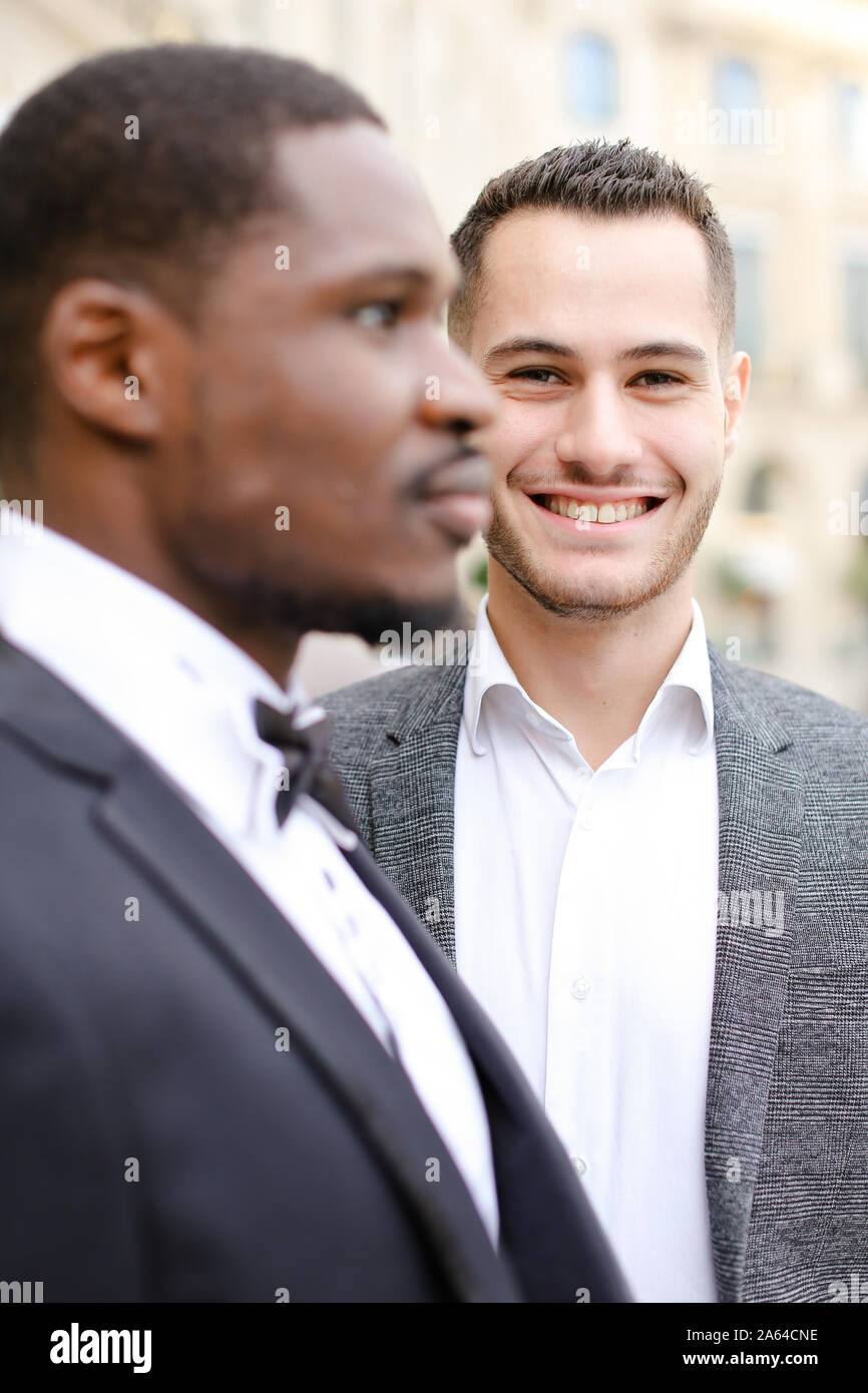Focus on caucasian man wearing suit standing near afro american male ...