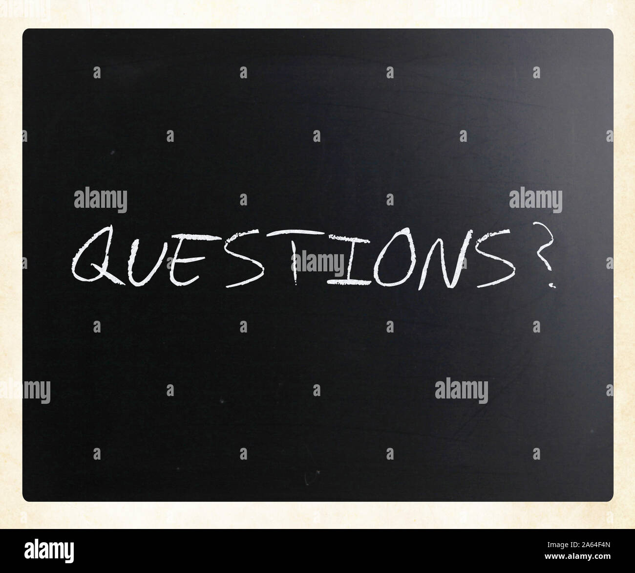 "Questions?" handwritten with white chalk on a blackboard Stock Photo