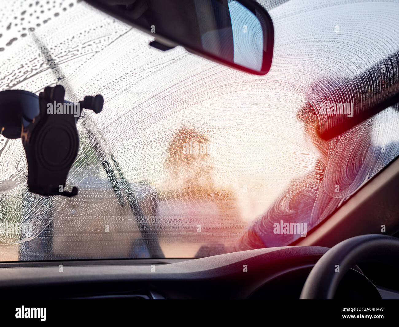 Windshield washing. Staff using squeegee cleaning the windshield, view