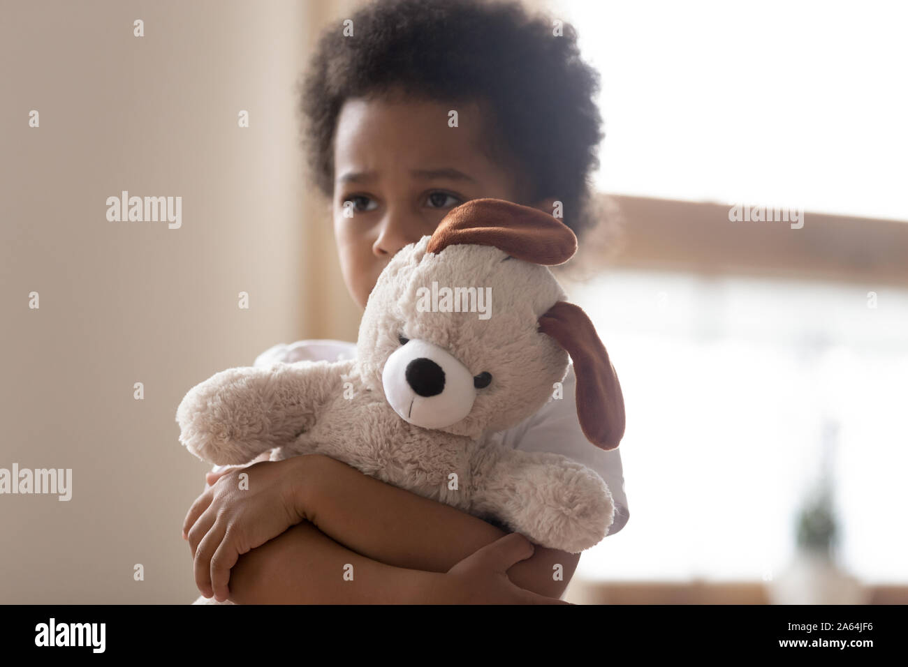 Hurt small biracial boy hold toy feeling lonely Stock Photo