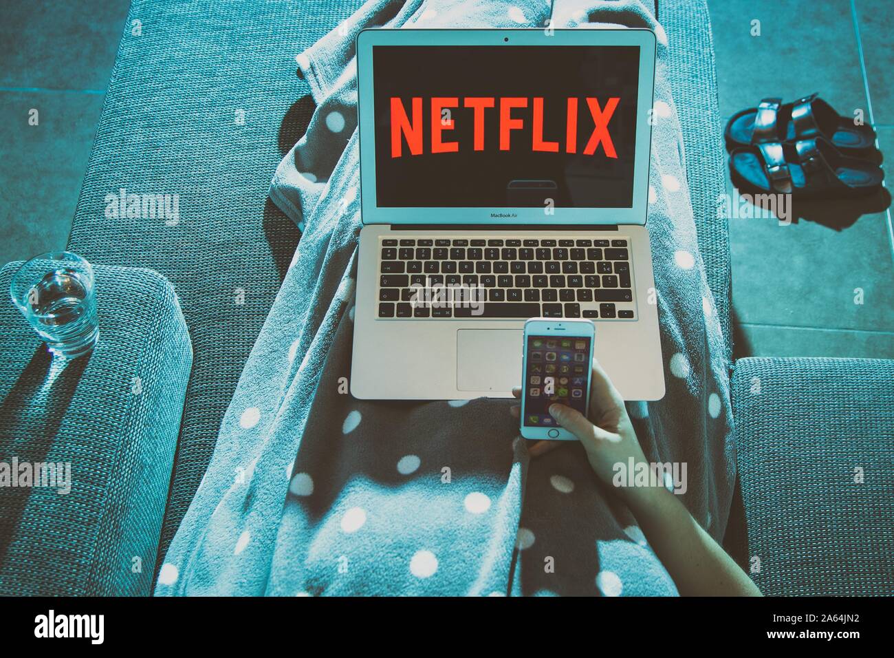 Digital composing, hand with smartphone on a couch with Netflix logo on a laptop screen, Belgium Stock Photo