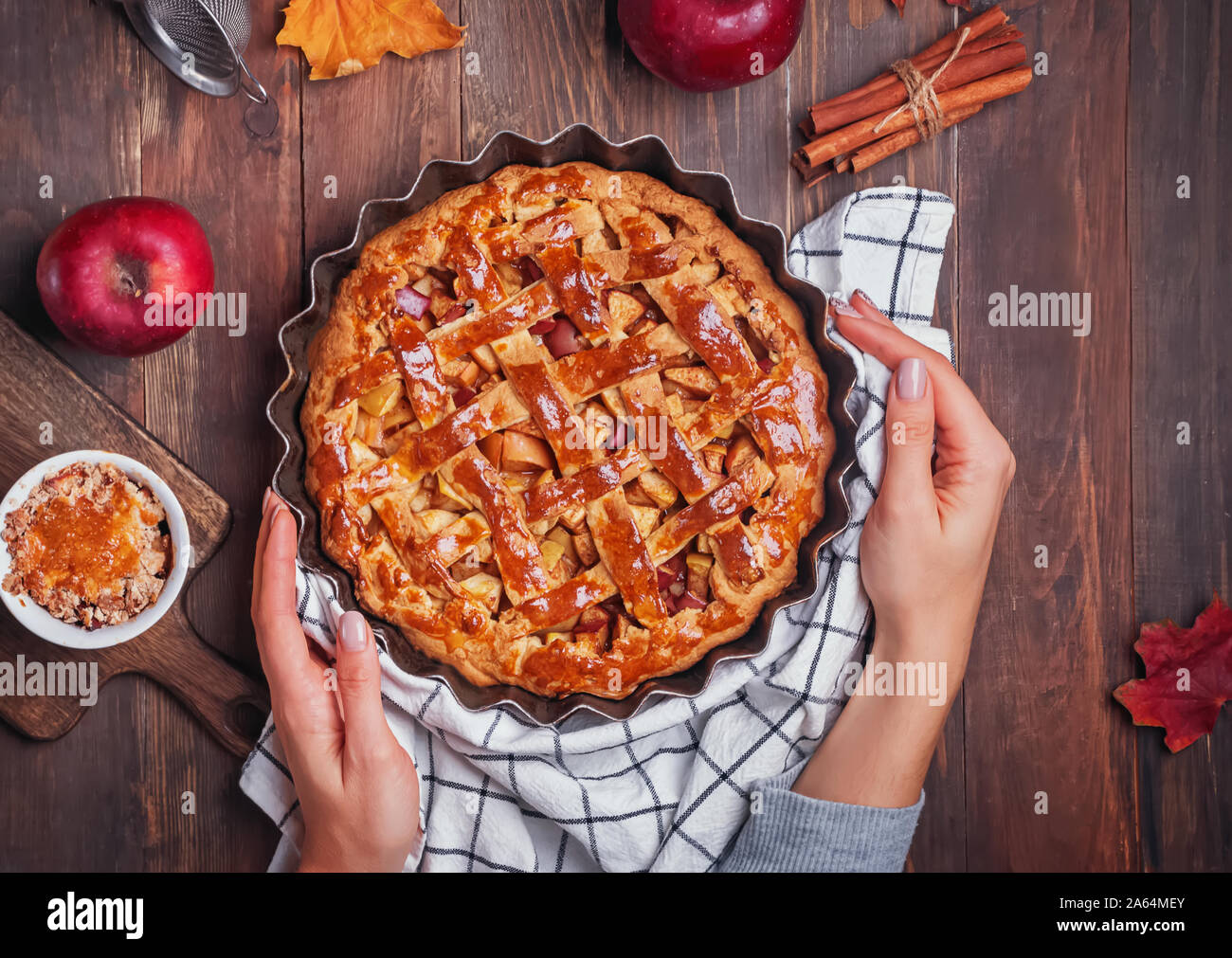 Woman's hands putting fresh baked apple pie on wooden table Stock Photo