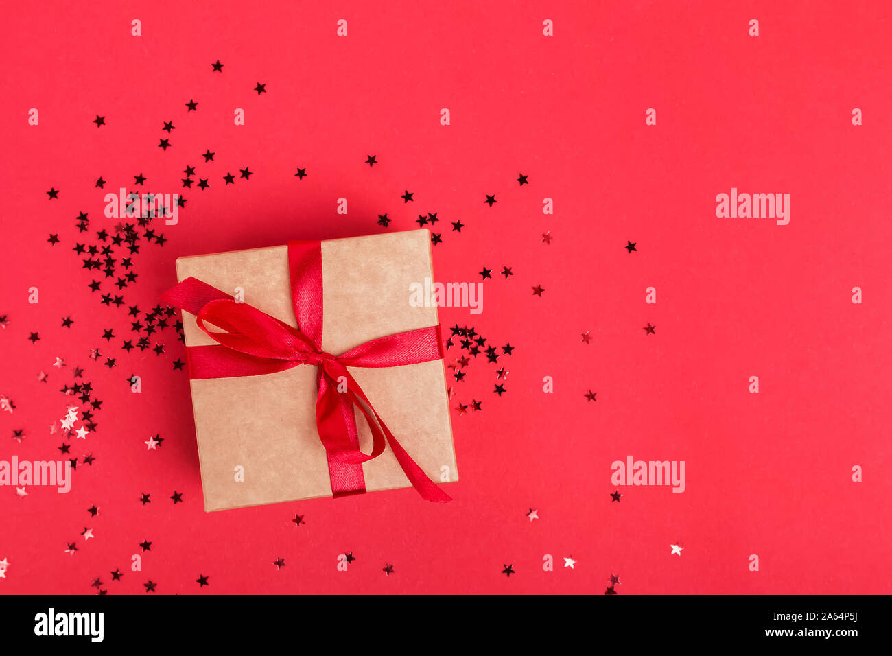 Giftbox with red ribbon on the red background. Stock Photo