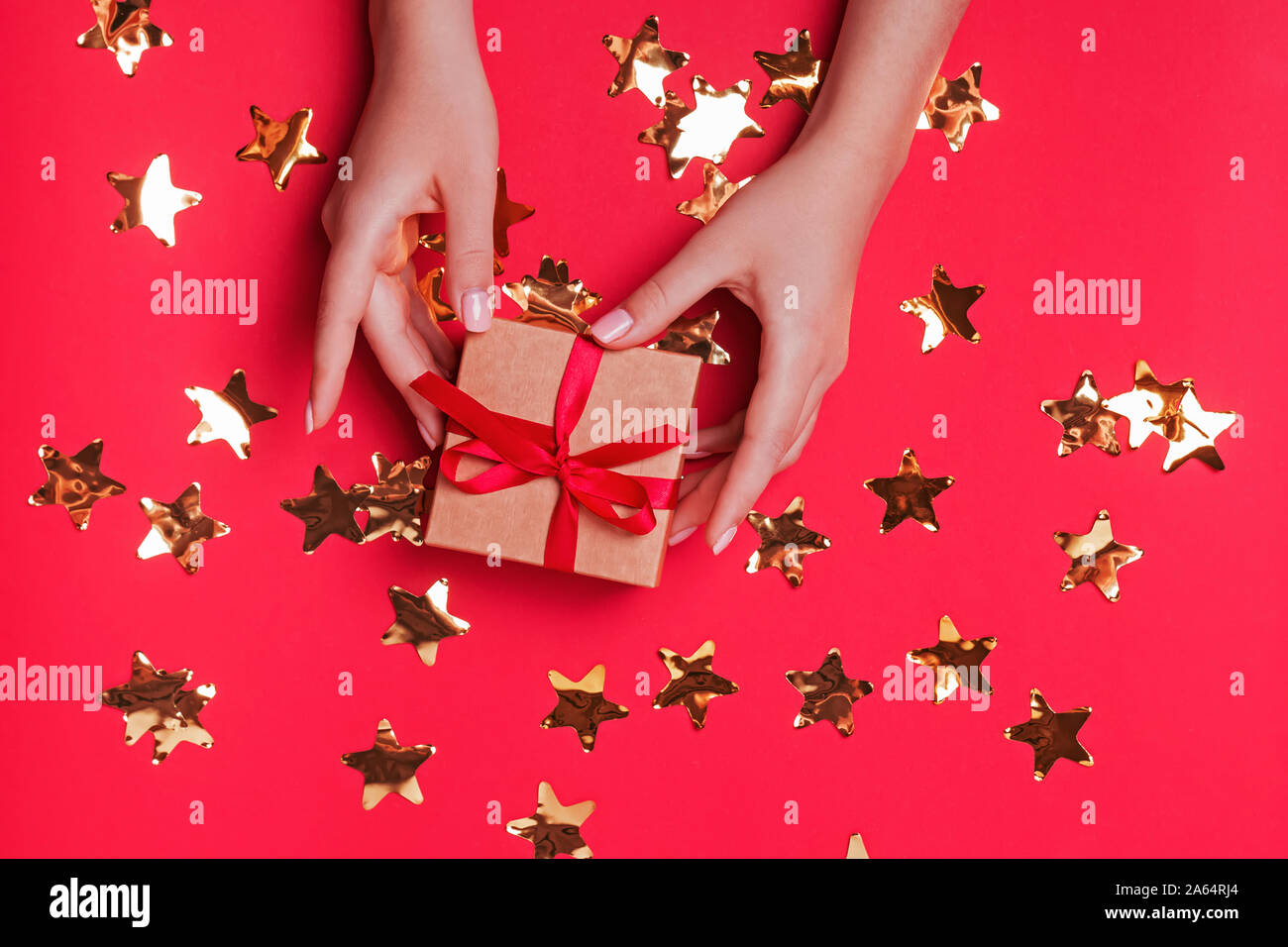 Woman's hands holding small giftbox on the red background Stock Photo