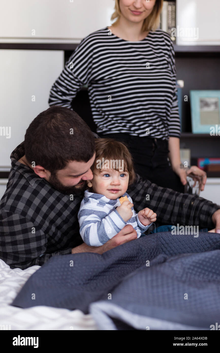 Young parents playing with their 8monthold baby in bed Stock Photo