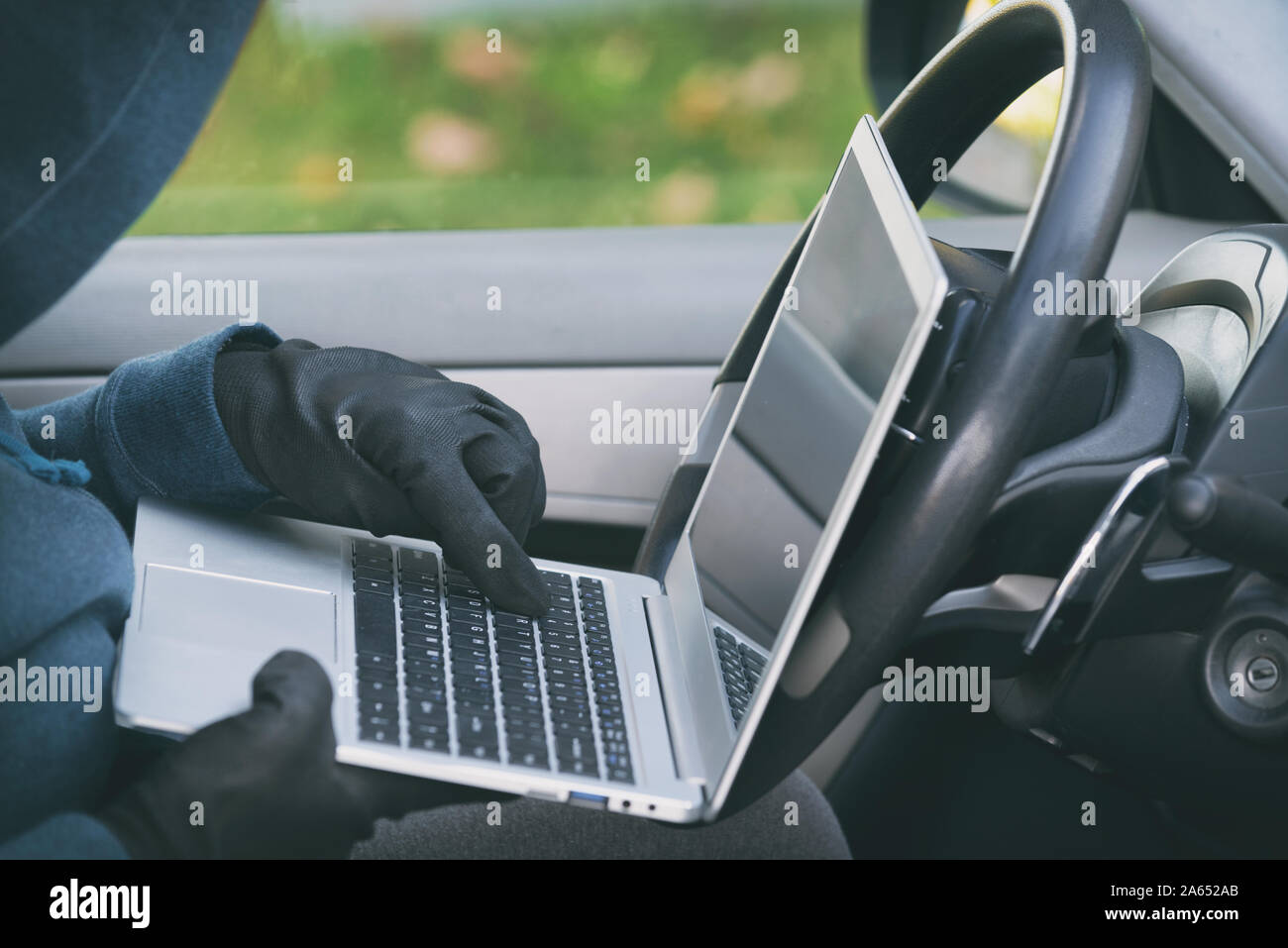 Hooded thief tries to break the car's security systems with laptop