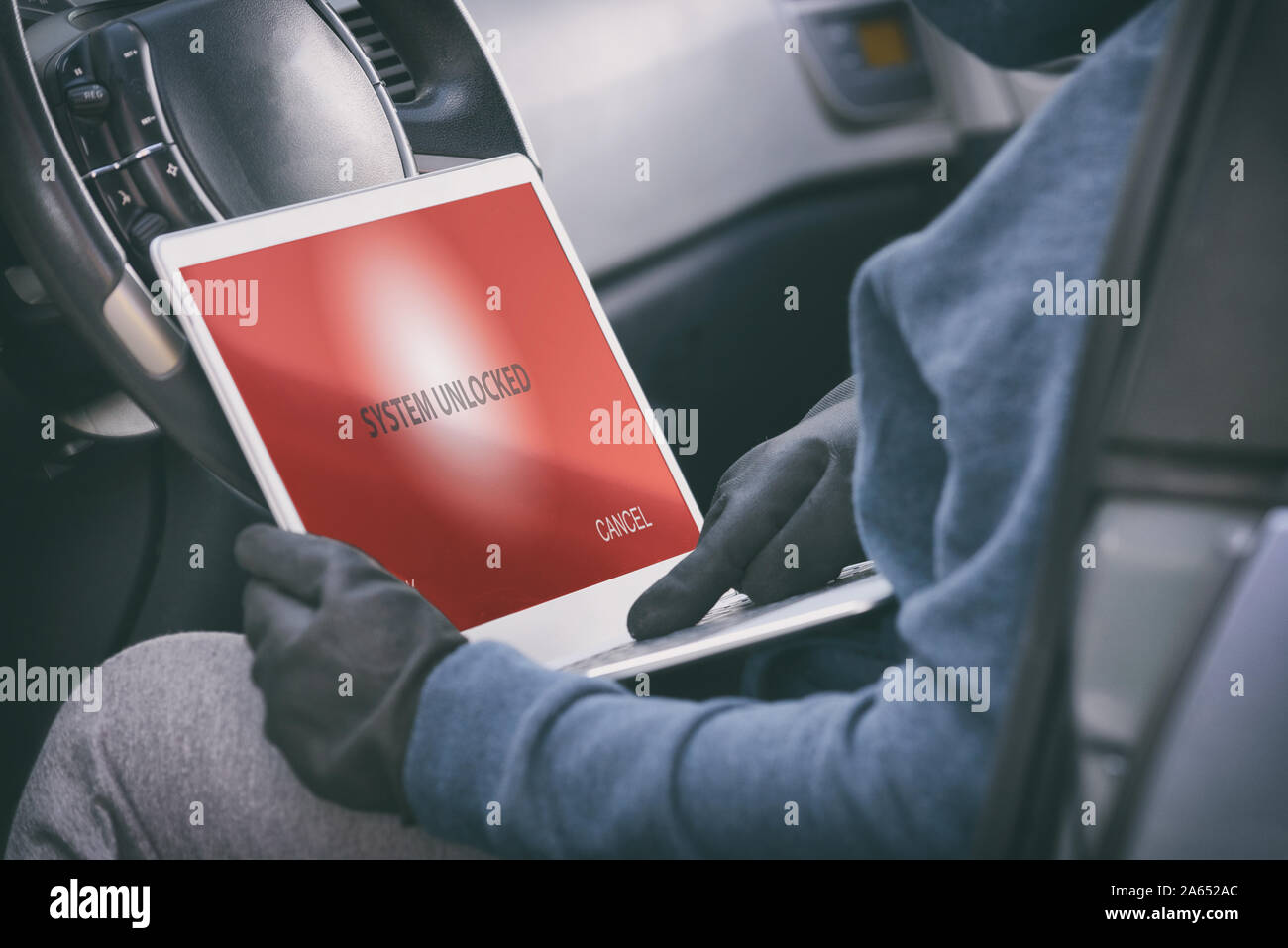 Hooded thief tries to break the car's security systems with laptop
