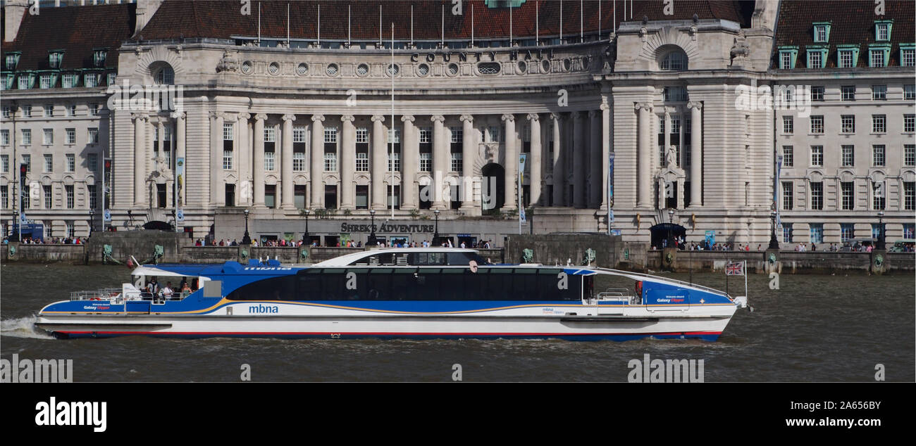 A river, mbna, passenger boat, on the River Thames at Westminster, London, going upstream in front of City Hall on a sunny day with many sightseers Stock Photo