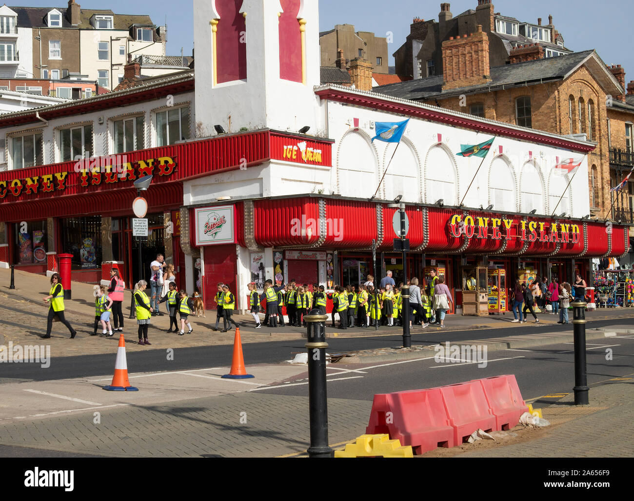 School Children in High Visibility Jackets in a Crocodile Walking Past Coney Island Amusement Centre in Scarborough North Yorkshire England UK Stock Photo