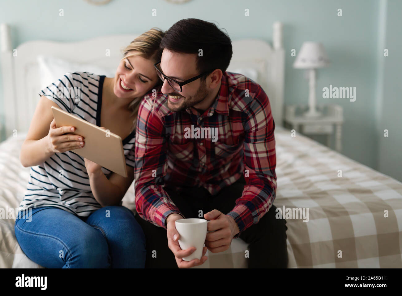 Young attractive couple using tablet in bedroom Stock Photo