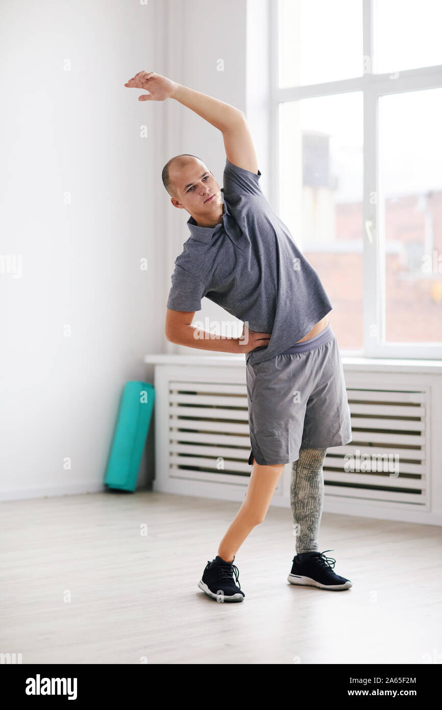 Young disabled man standing raising his arm and stretching during