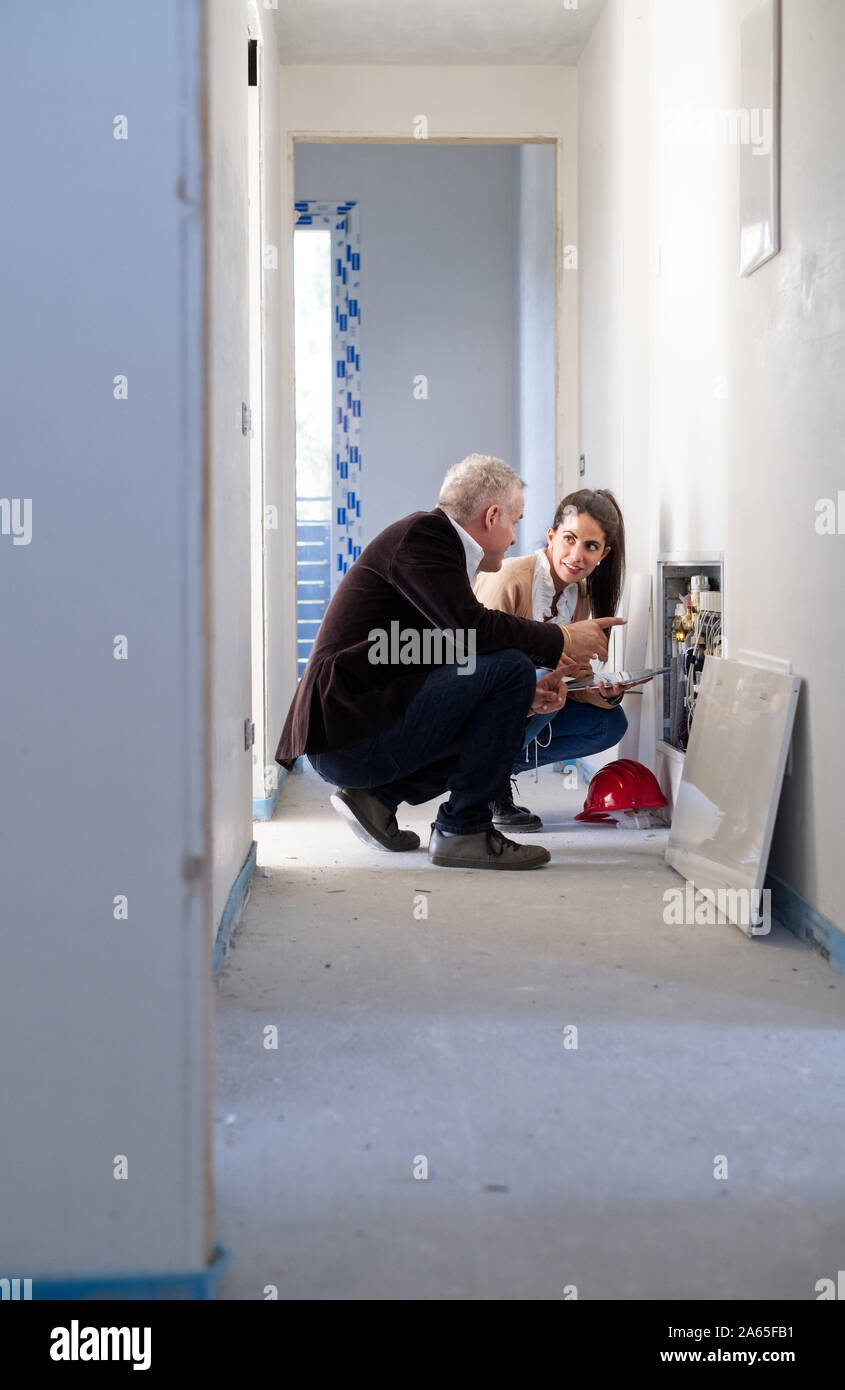 Architect Showing Heating System To Assistant In Construction Site Stock Photo