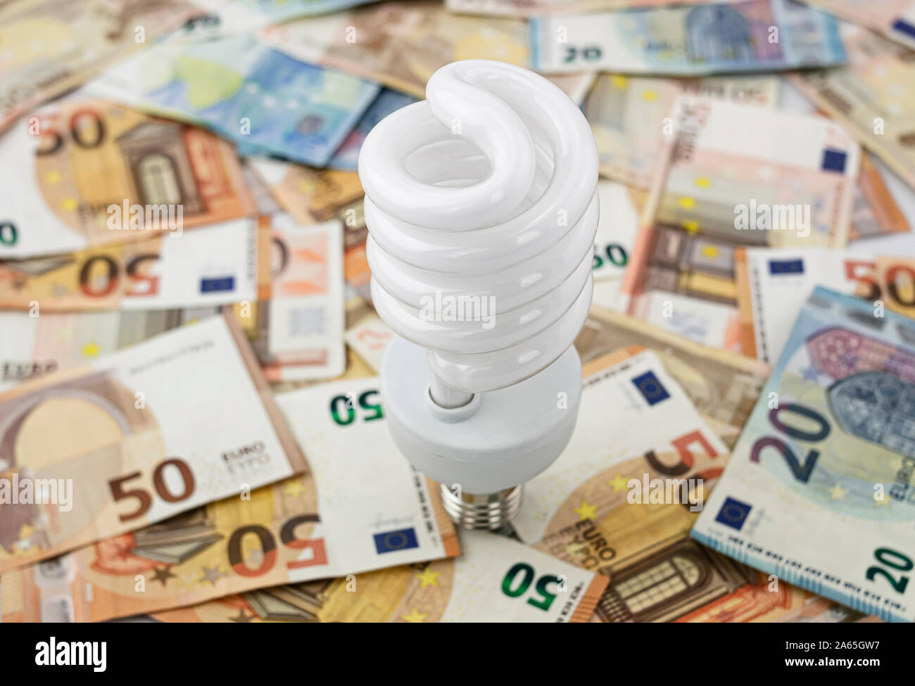 Metaphor about the excessive cost of light, energy and electricity, using a white halogen bulb on a bed of twenty and fifty euro bills Stock Photo