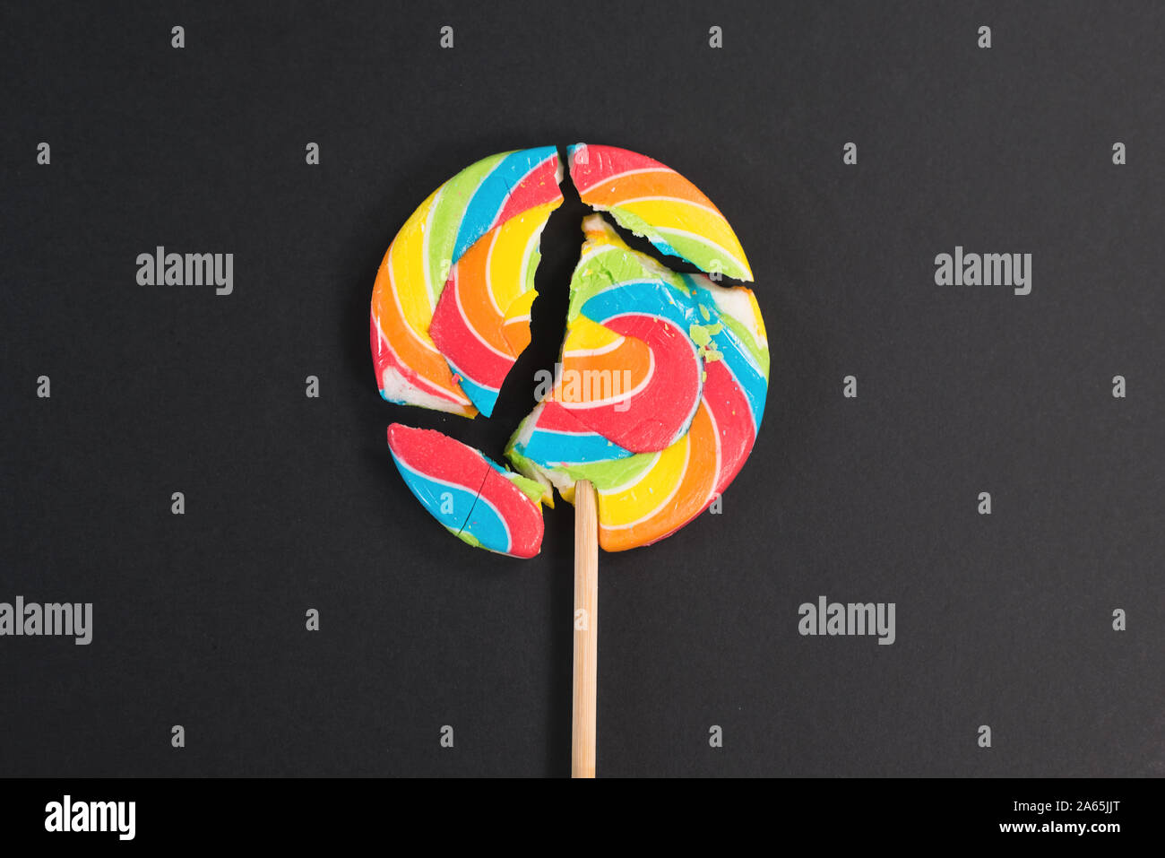 Swirl round broken lollipop on black background. concept of unhealthy ...