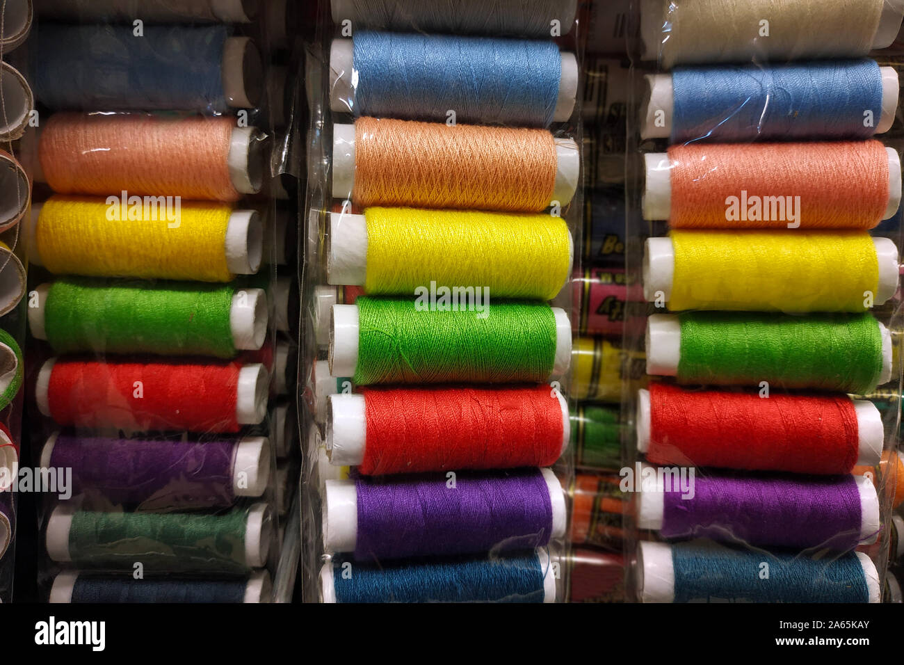 Multi-colored sewing threads close-up. Skeins of thread of different colors on the counter in the store. Threads for sewing. Stock Photo