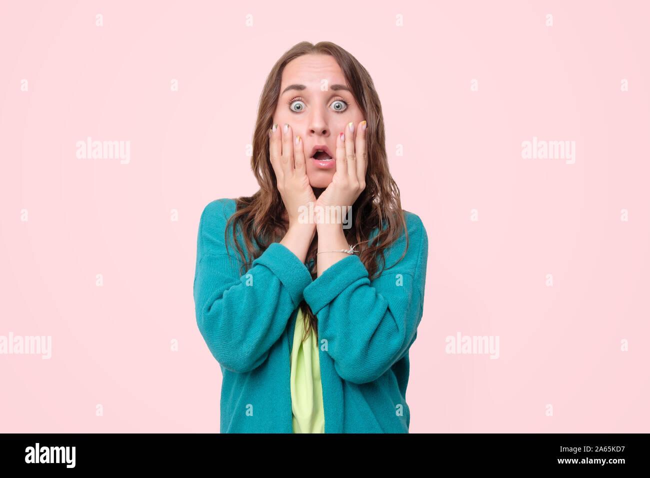 Woman with opened mouth and big eyes holding hands near face and looking happy Stock Photo