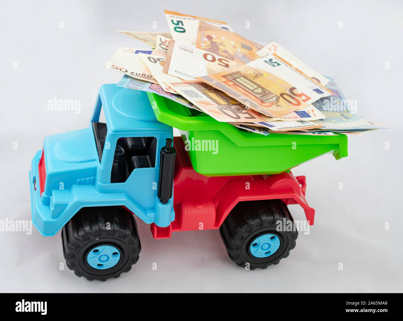 Colorful plastic truck carries a large number of 50 and 20 Euro bills on top of it Stock Photo