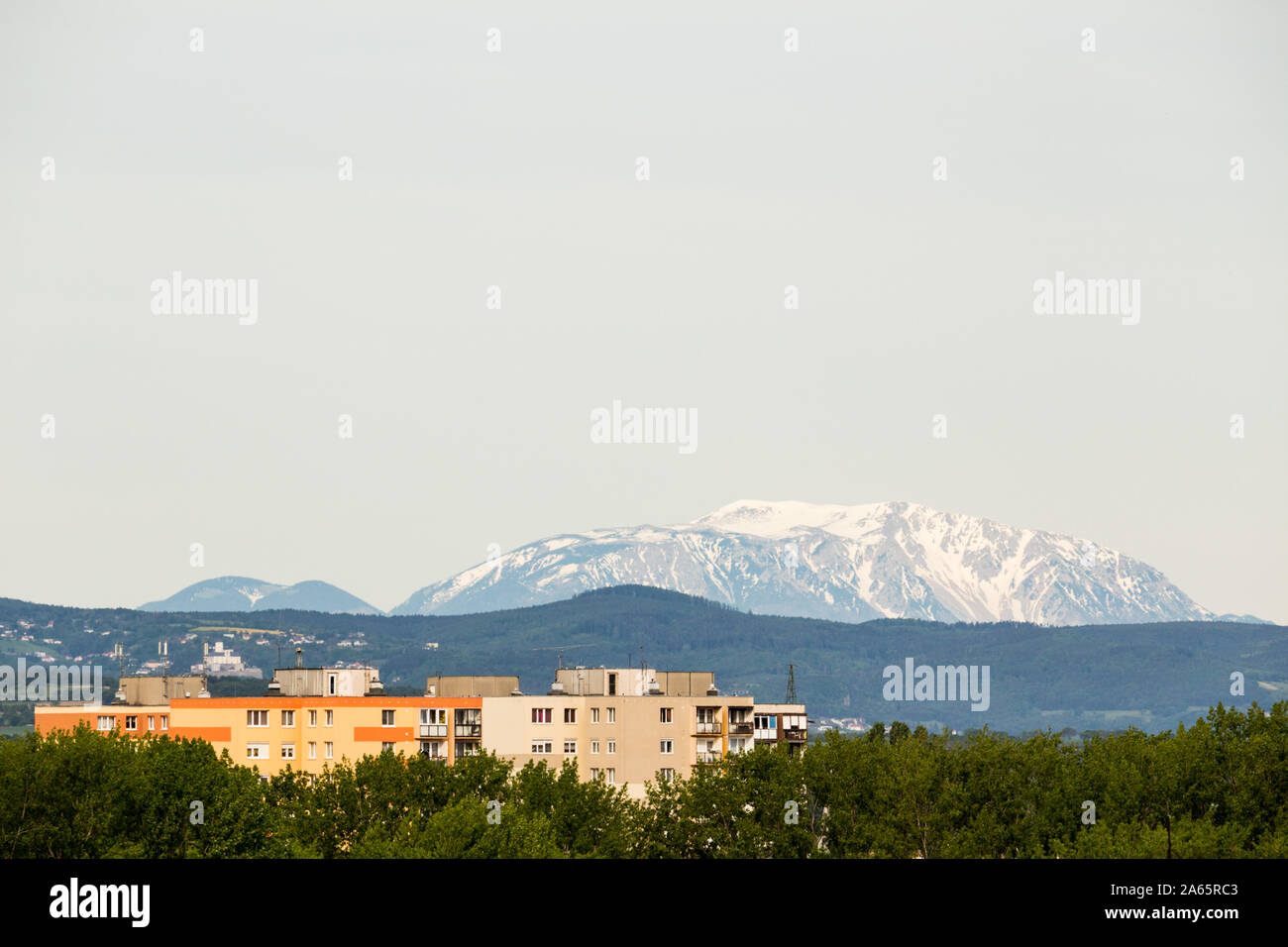 Mountain Schneeberg and Rax in clear weather with top of residential blocks buildings in the foreground, seen view from Sopron, Hungary Stock Photo