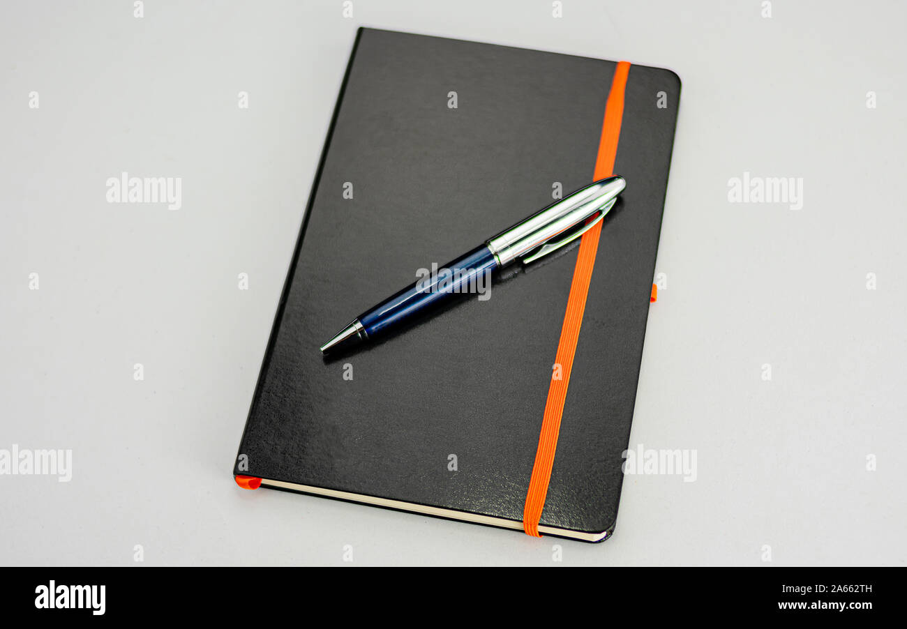 Bound notepad with black hardcover and modern blue and silver pen Stock Photo
