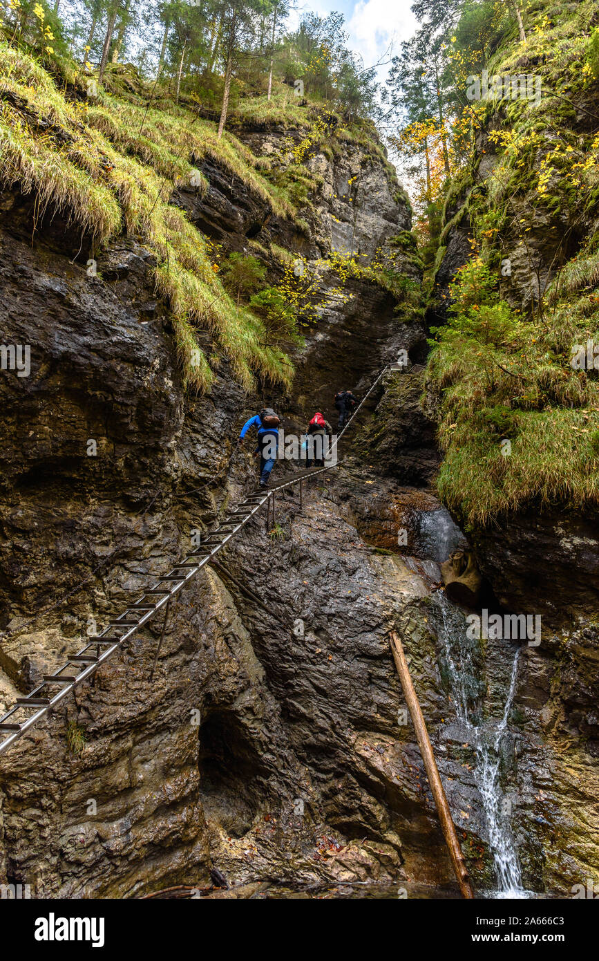 People climbing the metal ladders by a waterfall on the Sucha Bela hiking trail in autumn Stock Photo