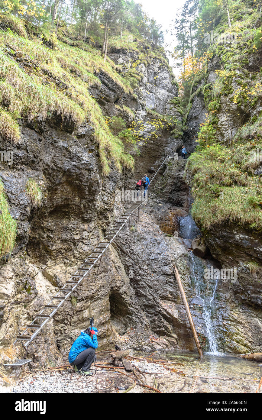 People climbing the metal ladders by a waterfall on the Sucha Bela hiking trail in autumn Stock Photo