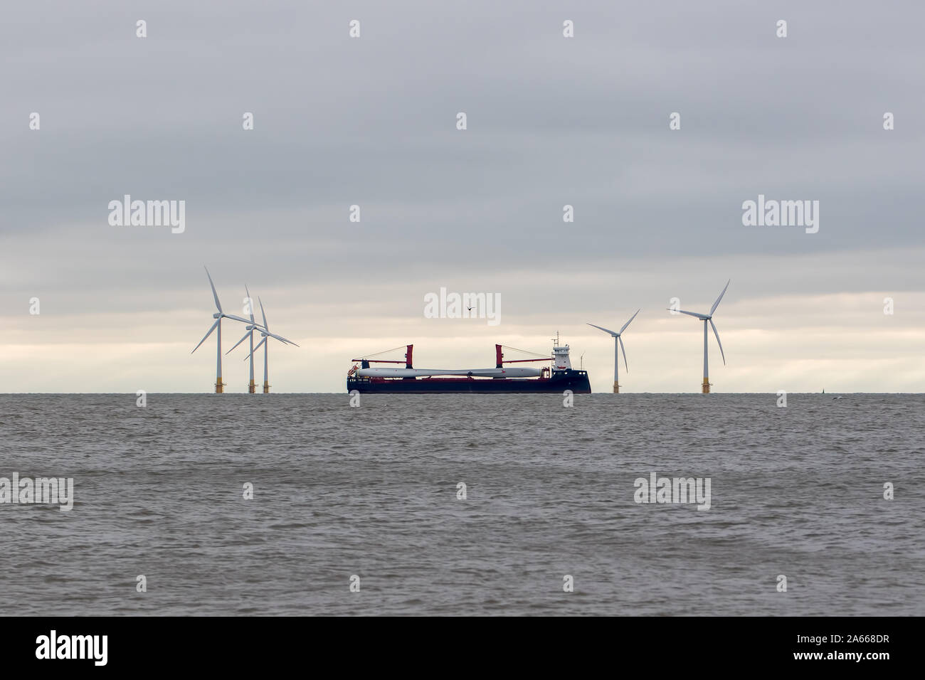Wind turbine parts. Clean energy investment. Ship transporting blades via Scroby sands offshore wind farm Norfolk UK, a renewable green energy investm Stock Photo