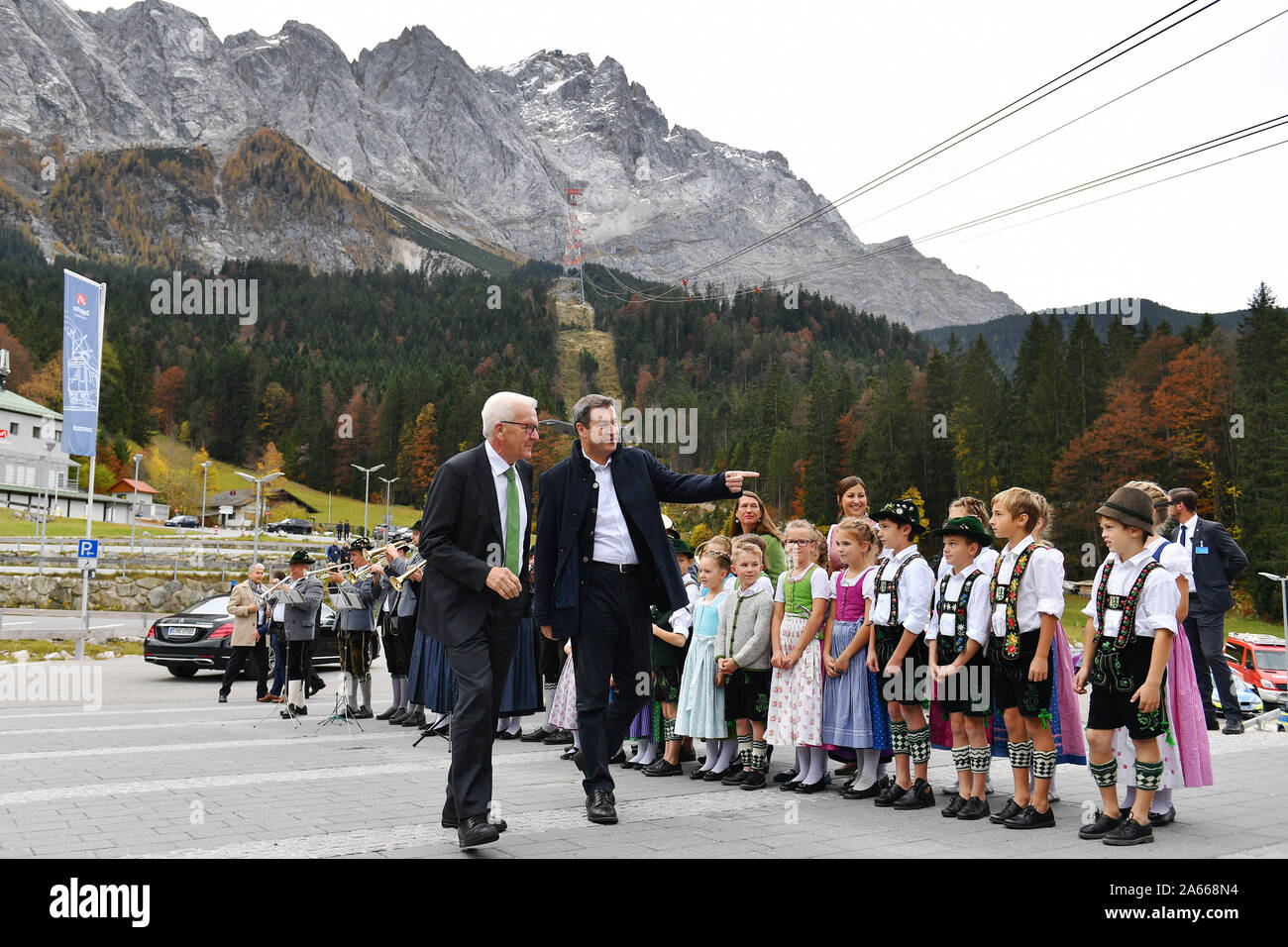 Markus SOEDER (State Premier of Bavaria and CSU Chairman) greets Winfried KRETSCHMANN (Minister President Baden Wuerttemberg) at the base station of the Zugspitzbahn, accompanied by children in traditional Bavarian costumes. In the backyard the Zugspitze. Prime Minister Soeder invites to the annual conference of the heads of state and government at Schloss Elmau on 24. and 25.10.2019. | usage worldwide Stock Photo