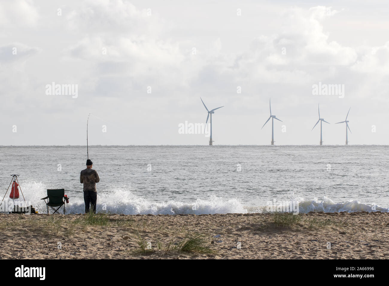 Alternative lifestyle and green living fisherman. Sustainable resource fishing. Wind power and renewable wave energy represented with offshore windfar Stock Photo