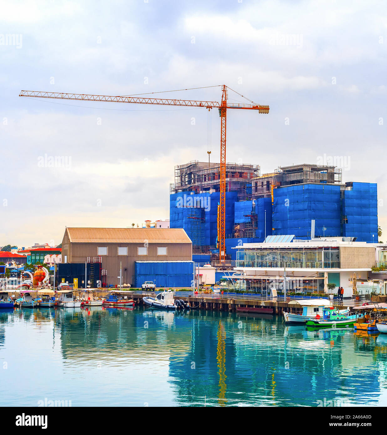 Construction site by Limassol waterfront, boats moored in marina with cafes and restaurants, Cyprus Stock Photo