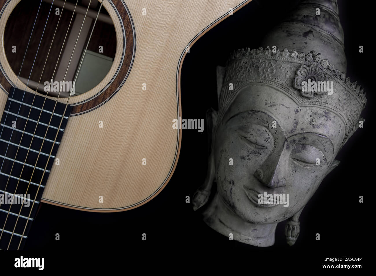 Spiritual music. Traditional meditating buddha statue with acoustic folk guitar. Representing music therapy, religious music and healing the mind. Chi Stock Photo