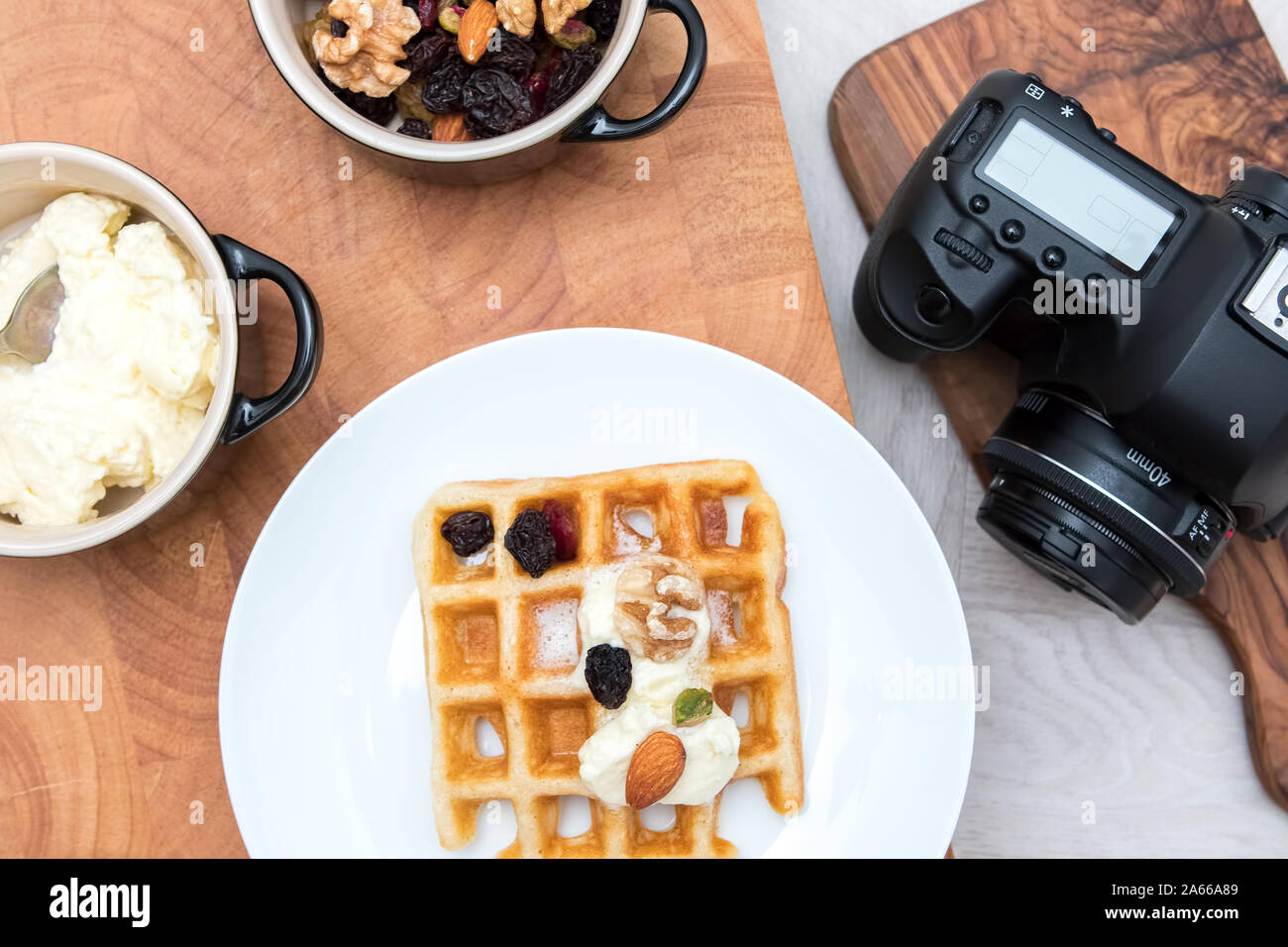 Food photography. Flat lay image of dessert meal with camera. Sweet fruit and nut waffles with fresh cream with waiting studio camera. Stock Photo