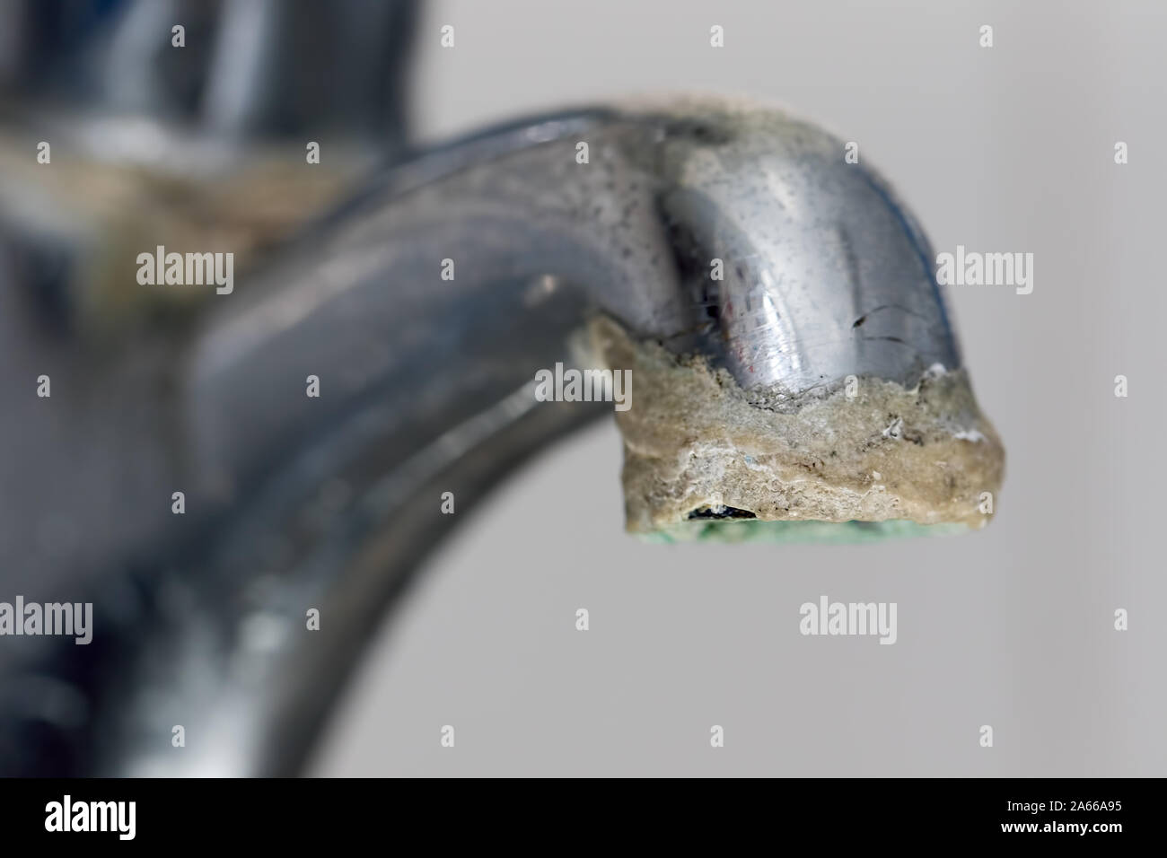Close-up of limescale build-up. Selective focus on hard water deposit on old tap spout. Chrome kitchen or bathroom faucet with crusty calcium carbonat Stock Photo