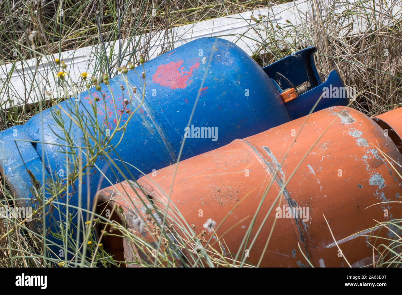 Fly-tip with gas canister bottles. Toxic hazardous waste fly tipping. Irresponsible environmental damage and danger caused by illegal rubbish dumping. Stock Photo
