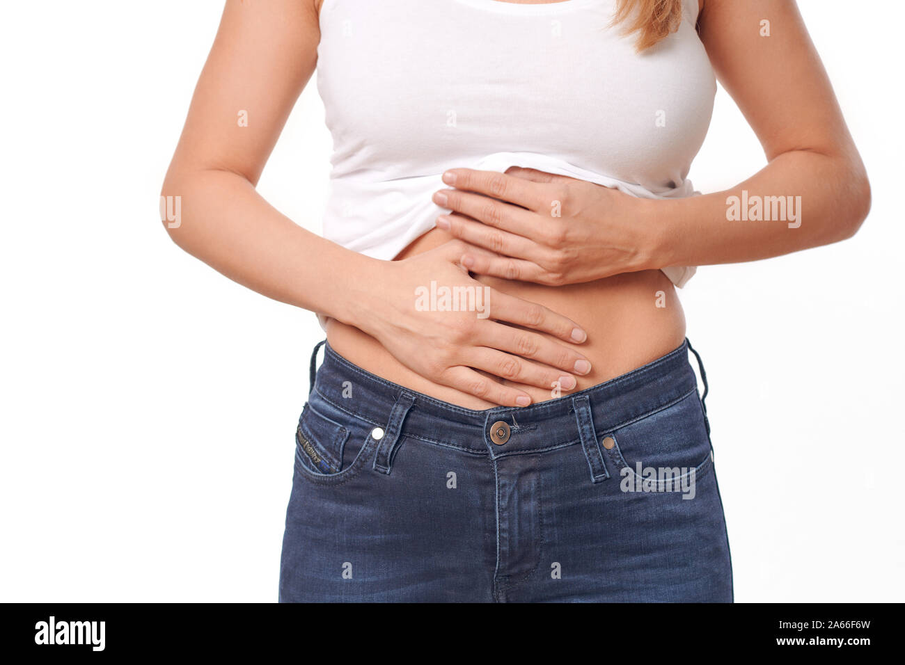 Woman with her monthly menstrual pains clutching her stomach with her hands as she becomes stressed by the ongoing cramps, torso view of her hands and Stock Photo