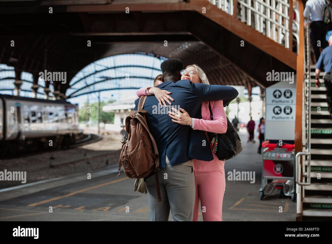 A male and female co-worker parting ways after work. They are hugging each other goodbye. Stock Photo