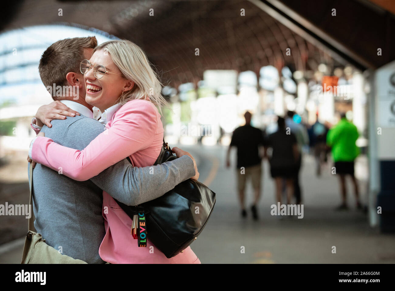 A male and female co-worker parting ways after work. They are hugging each other goodbye while laughing. Stock Photo