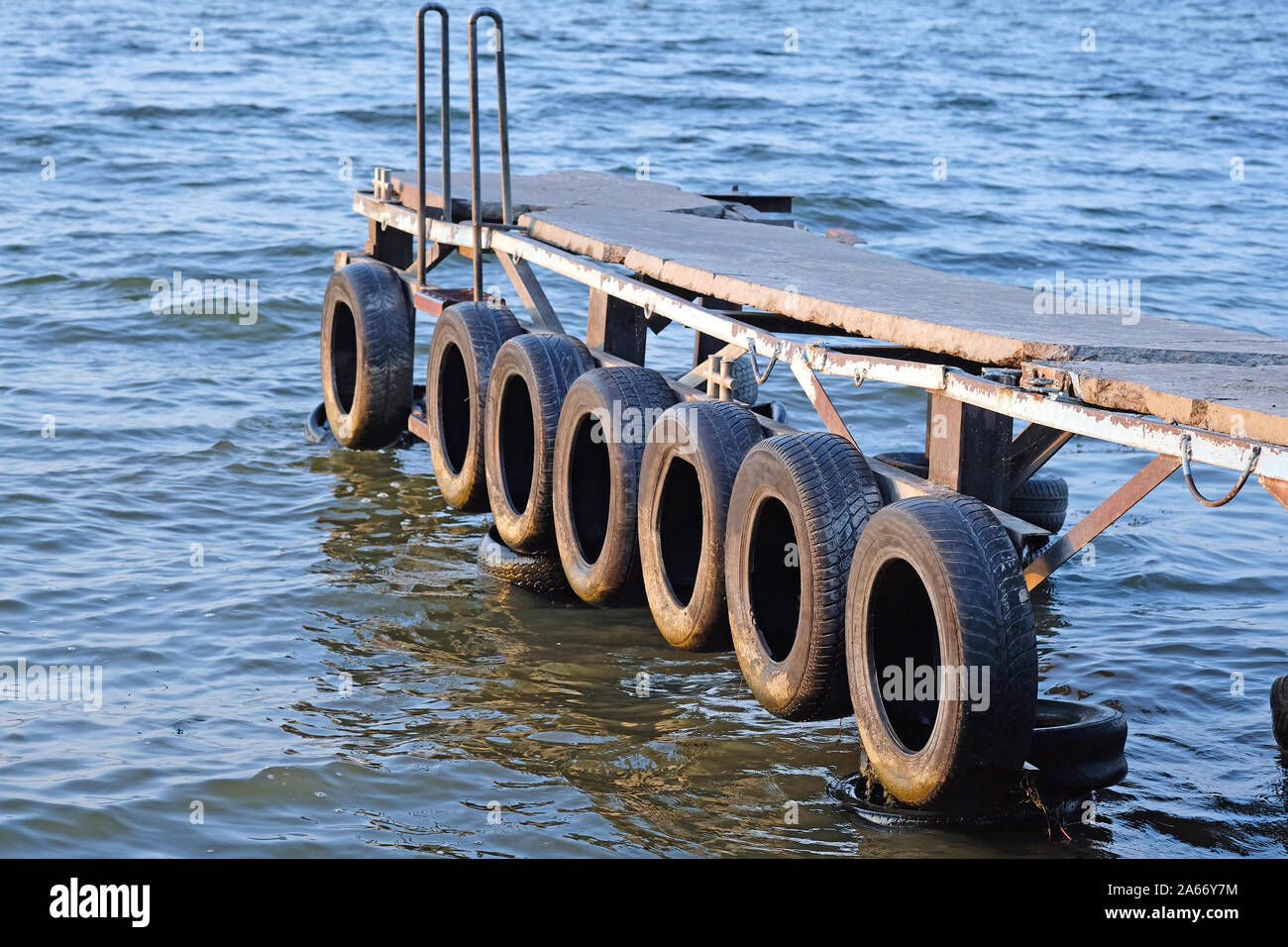 Wooden pier on the river close-up. On the side of the pier are old  automobile tires. Old boat mooring on the river Stock Photo - Alamy