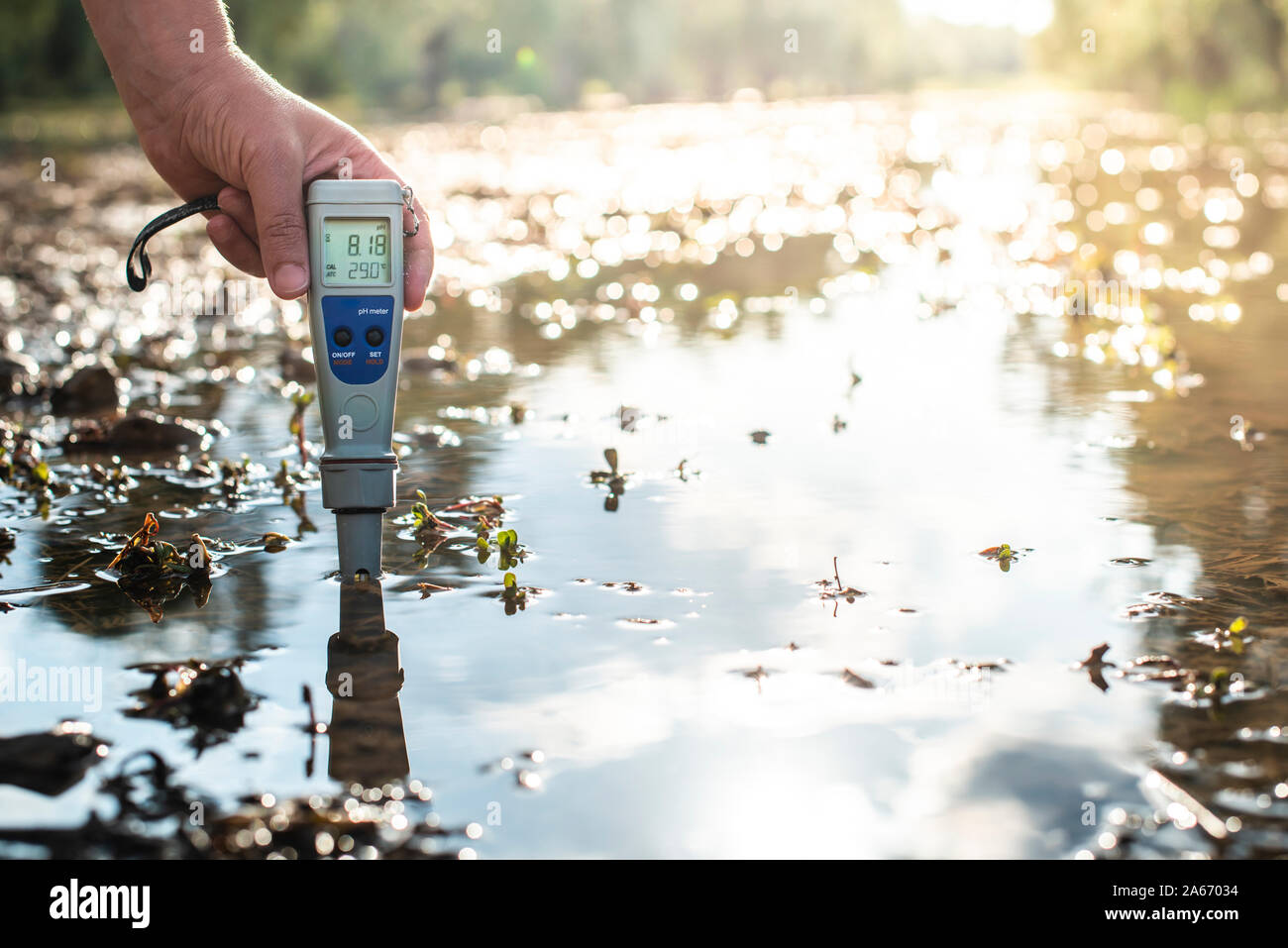 Measure water content with digital device. Sunrise over the water. PH meter. Stock Photo