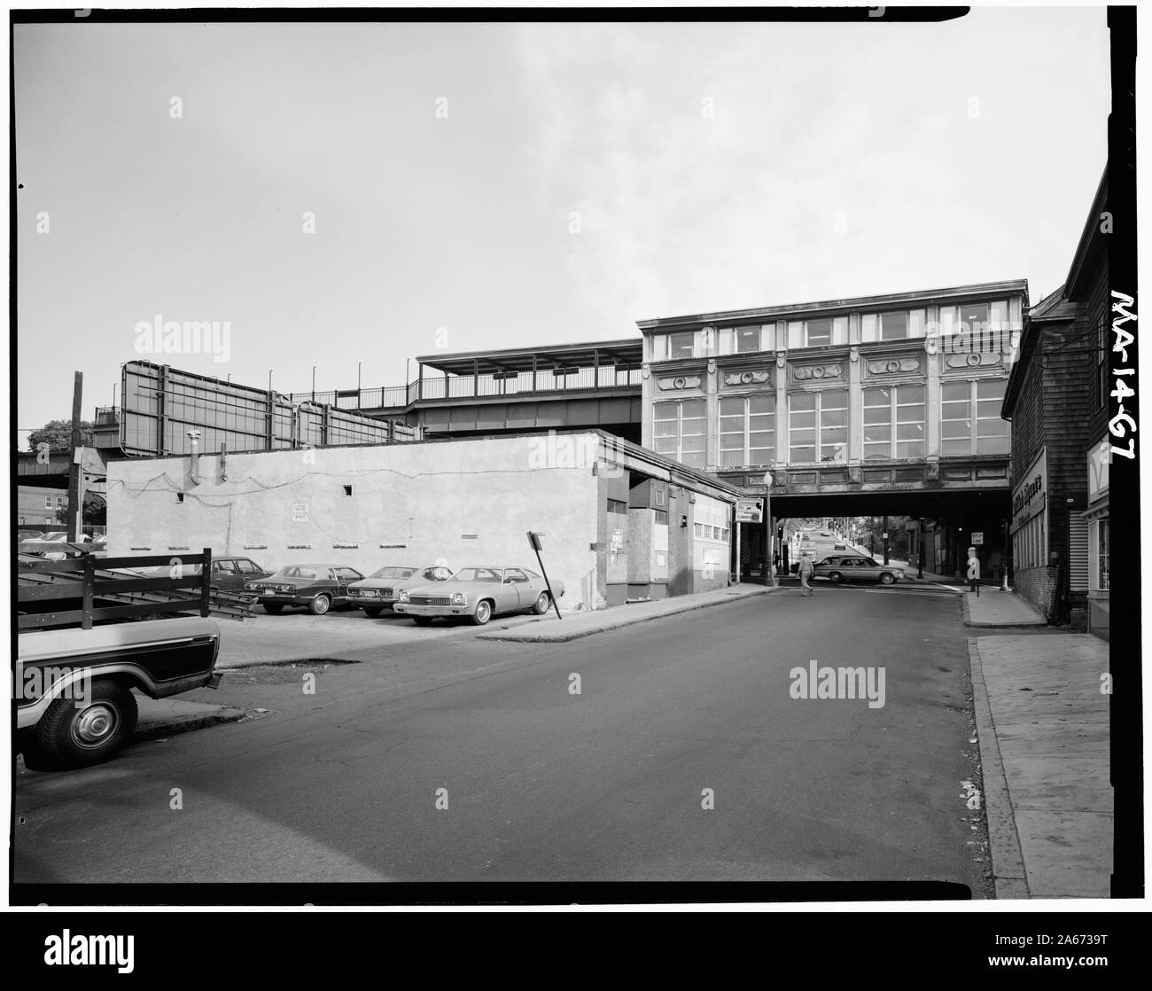 1982 photograph of Green Street station from the street belowOriginal caption:  West elevation Green Street station - looking East across Washington Street along Green Street. In foreground is the reconstructed version of the intermediate level passenger platform which was originaly suspended from the elevated structure. - Boston Elevated Railway, Elevated Mainline, Washington Street, Boston, Suffolk County, MA; Stock Photo