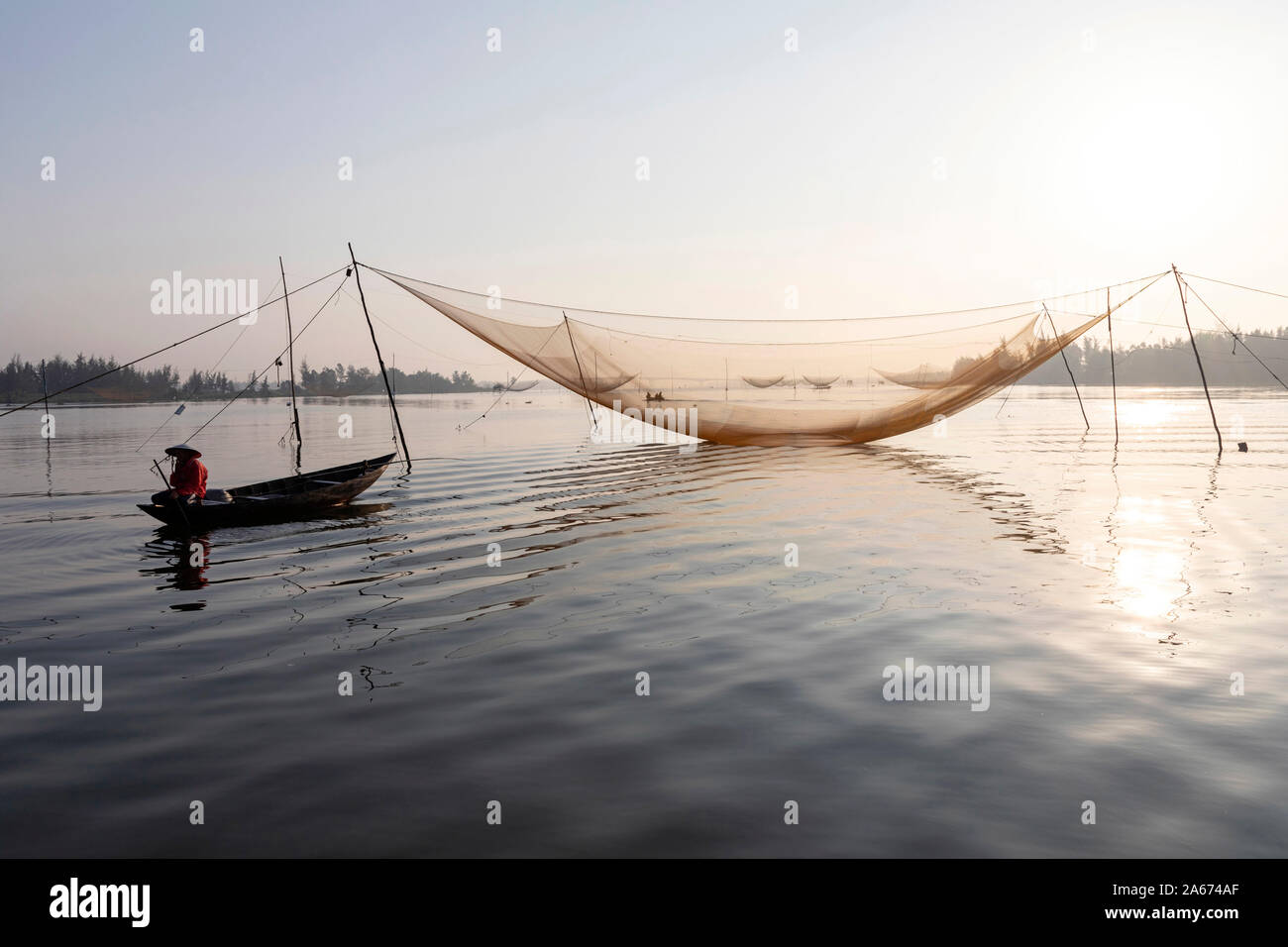 Fishermen row around fishing nets at sunrise, Thu Bon River, Quang Nam Province, Vietnam Stock Photo